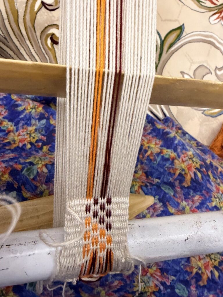 A Sadu pattern in brown and orange taking shape on the loom