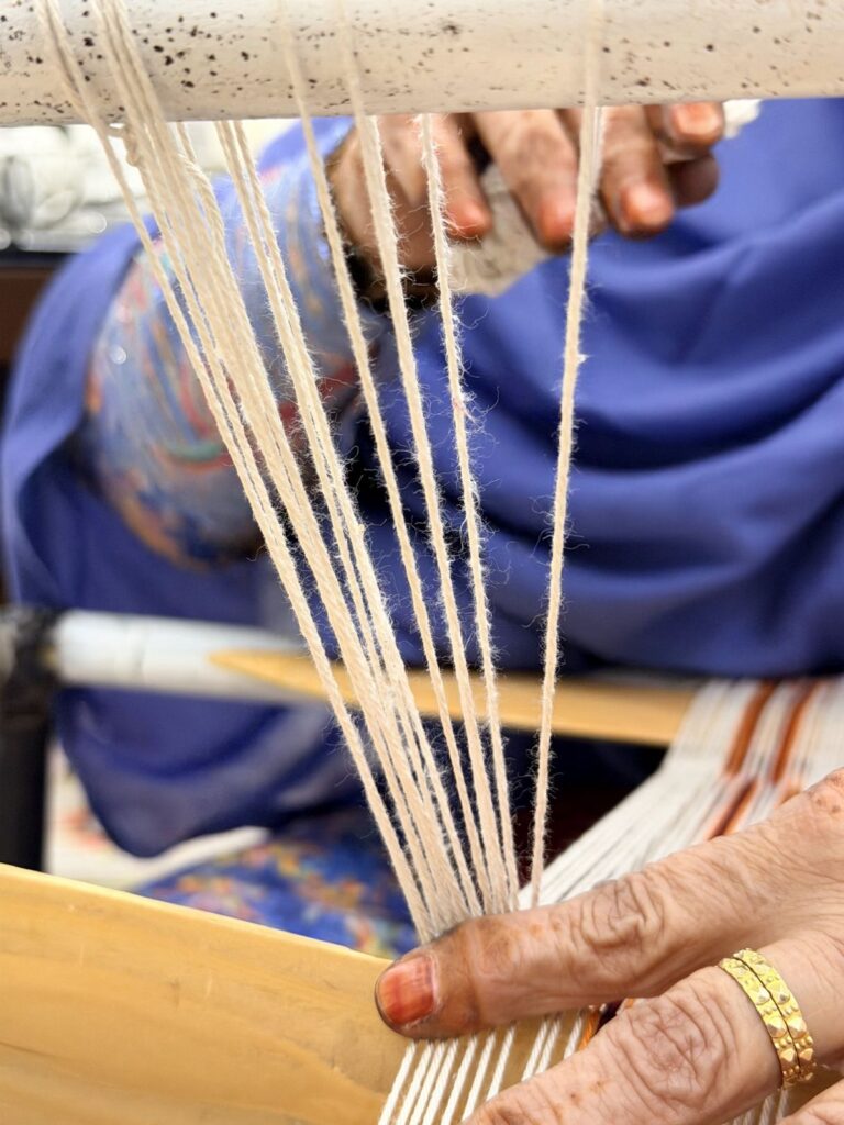 Hands setting up the white warp threads on a Sadu loom