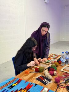 An Emirati artisan guiding a young weaver at the loom