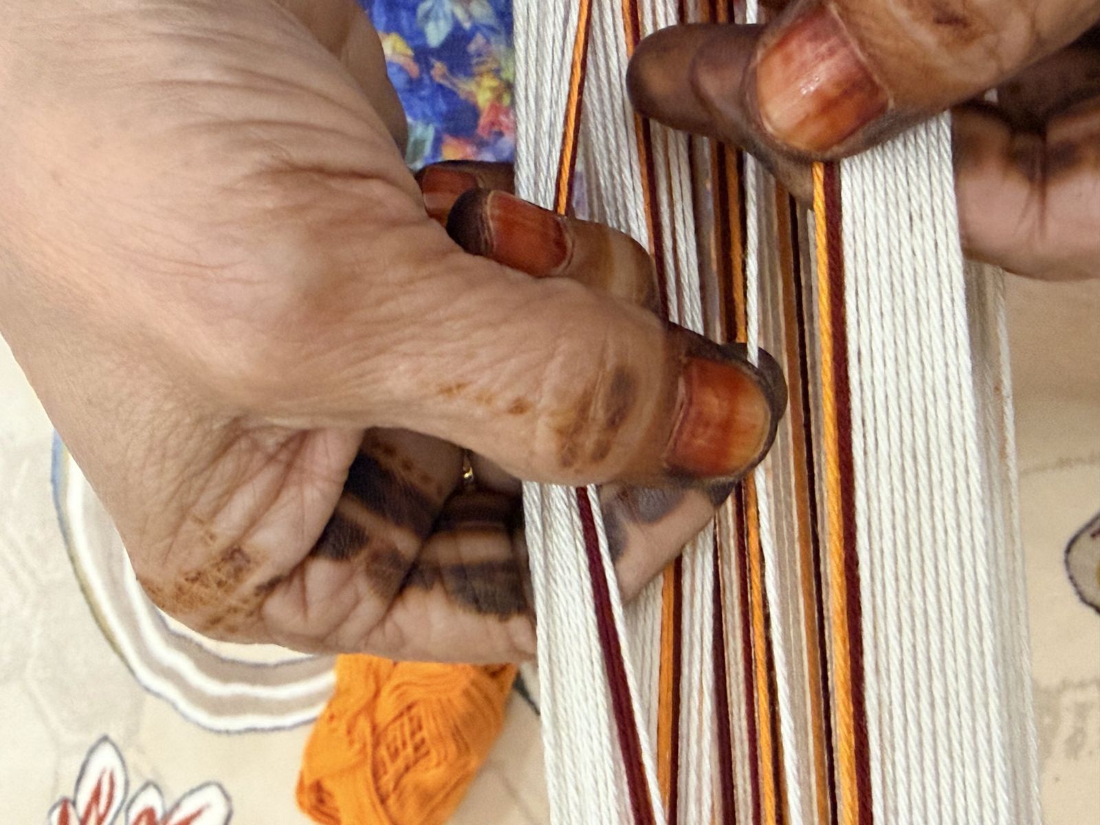 Umm Hamad weaving Sadu by hand, with red and orange warp threads