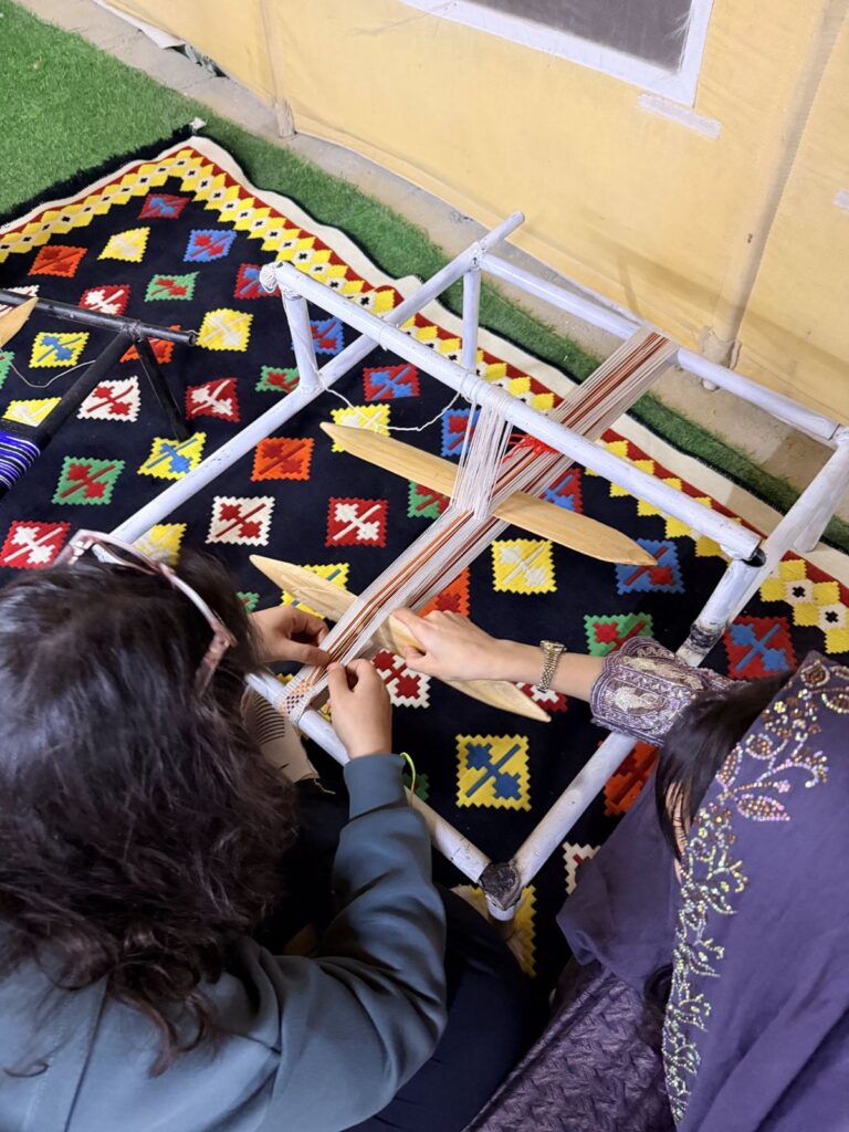 A visitor learning Sadu weaving with an Emirati artisan